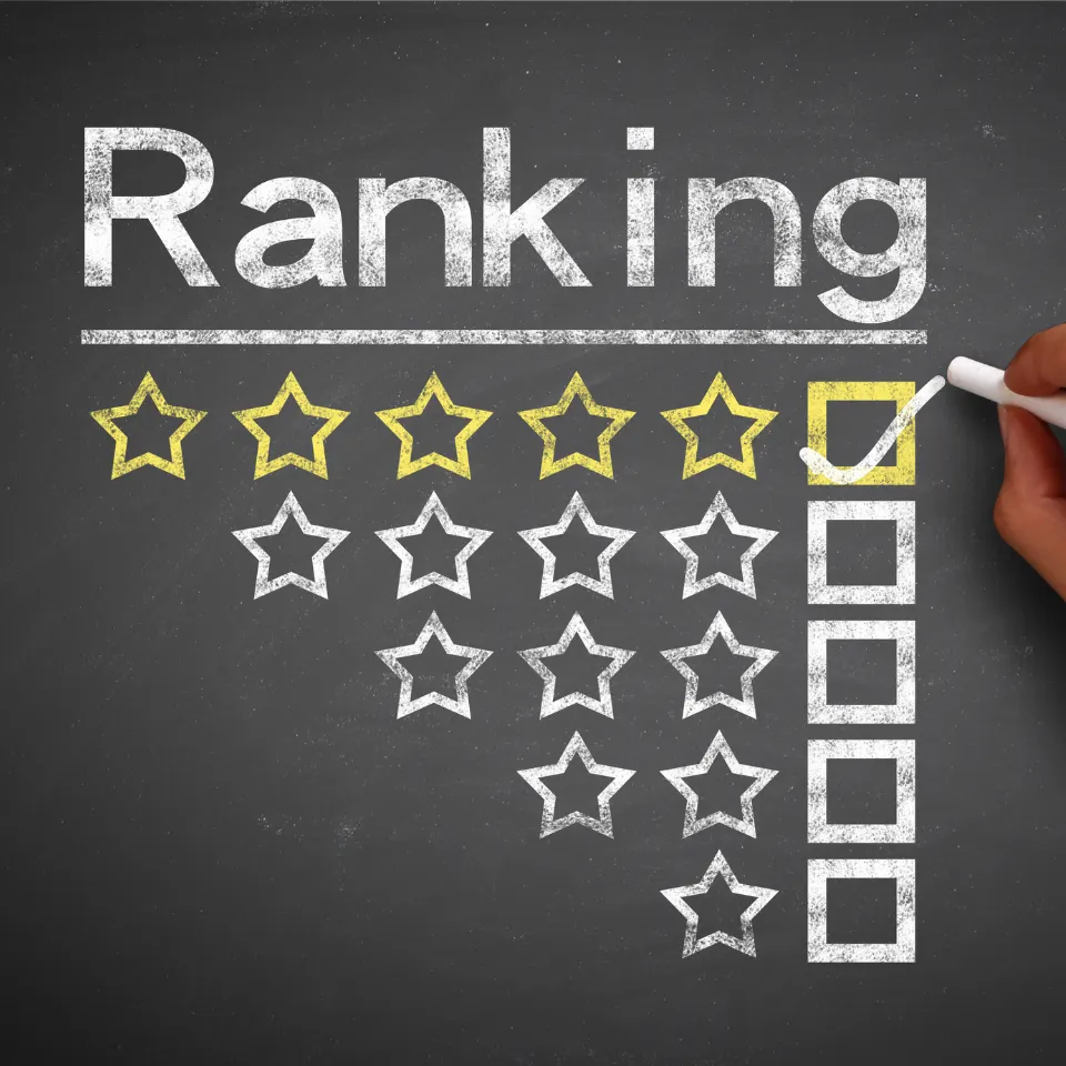 Hand drawing a five-star rating system with chalk on a blackboard under the word Ranking, highlighting the top rating option.